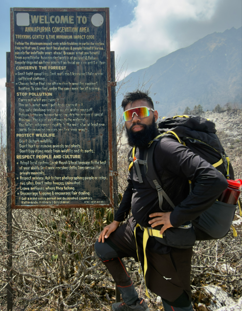 A guide beside a trail signboard in the Manaslu region